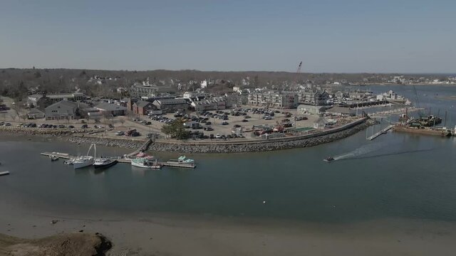 Aerial Drone footage of Scituate Harbor and Scituate main business district, Scituate MA.  Pan Right to Left showing industrial area and dock.  Also entrance to estuary.