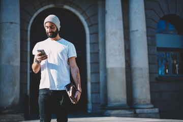 Turkish male blogger checking received text messages browsing website for chatting on smartphone...