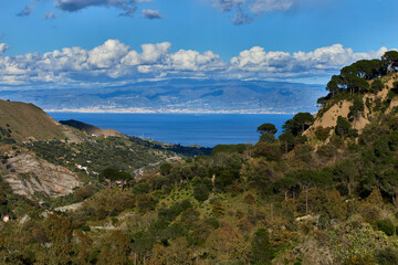 Fototapeta premium the green of Sicily overlooking the Strait, with valleys, villages and woods and clouds in the sky that cast shadows