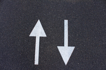 Pointers are two white arrows on an asphalt road, pointing in two directions. Decision making and...