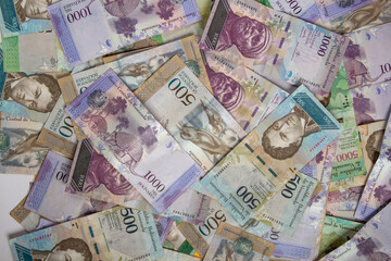 Fototapeta na wymiar montones de dinero venezolano a la vista superior uno encima del otro con números de 500 y 1000 bolívares, vista superior.