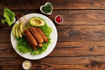 Tasty corn dog with sauce and salad served on white plate