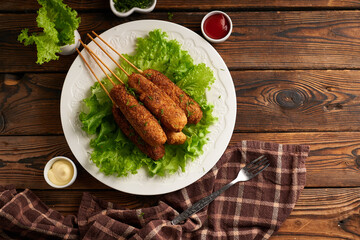 Tasty corn dog with sauce and salad served on white plate
