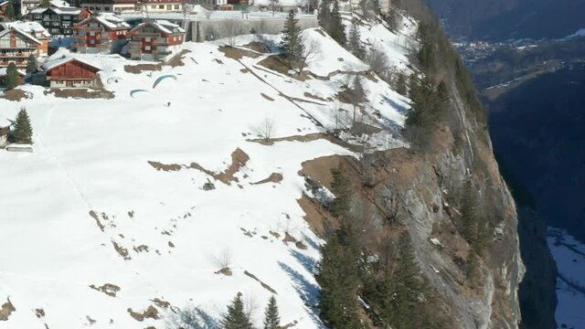 aerial of Paraglider jumping of edge of mountain near beautiful Swiss town - HD crop