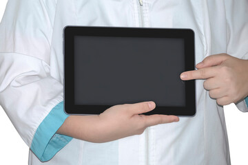 A medic in a white lab coat with a green frill on the sleeves points at a black blank tablet on a white background. Doctor With Tablet Computer.