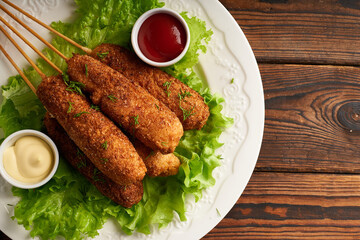 Tasty corn dog with sauce and salad served on white plate