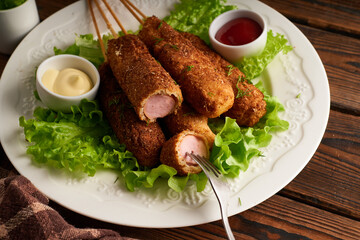Tasty corn dog with sauce and salad served on white plate