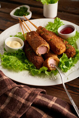 Tasty corn dog with sauce and salad served on white plate