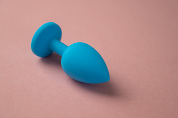 Blue anal plug on a pink background. Plastic sex toy for alternative sex. Copy space.