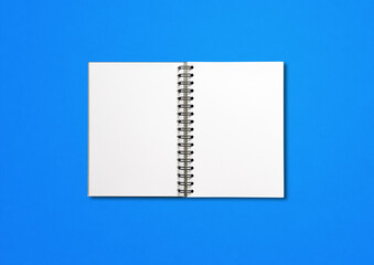 Blank open spiral notebook isolated on blue