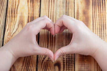 Hands in the shape of a heart of love, love concept. Wood background ..