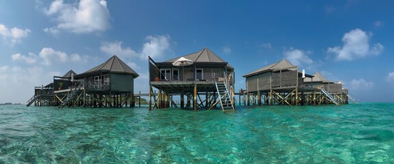 Panoramic View of Water Villa from Turquoise Laccadive Sea. Beautiful Overwater Bungalows during Day in Maldives.