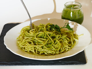 Tasty Spaghetti with homemade pesto sauce and a parsley leaf in a plate and a glass of pesto Sauce
