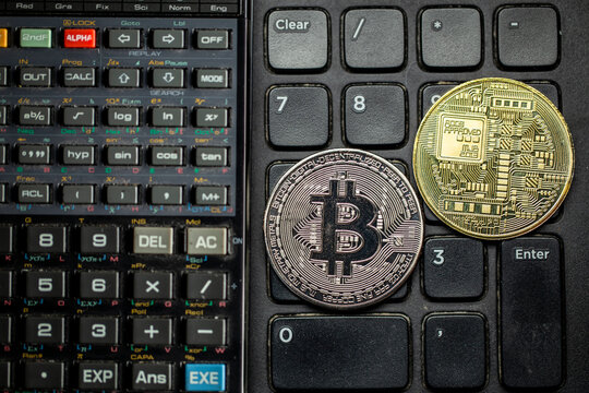 Criptomoedas Bitcoin em cima de teclado num&eacute;rico de computador com calculadora cient&iacute;fica. Tokens dourados e prateados em cima de bot&otilde;es.