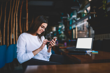 Satisfied woman surfing mobile phone while working