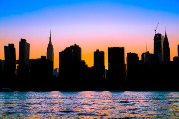 New York City skyline with silhouetted buildings and colorful sunset sky 