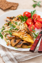 Omelet with mushrooms close-up. Tasty breakfast or lunch. Omelet with champignons, cheese, and tomatoes in a white plate on the table. 