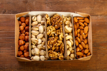 Assorted nuts in packaging on a brown wooden table.