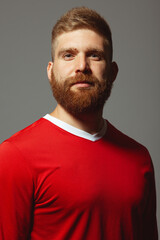 Portrait of proud handsome middle aged red-haired sportsman over gray wall. Red sportswear....