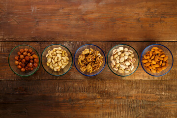 Assorted nuts in a glass bowl on a wooden table.