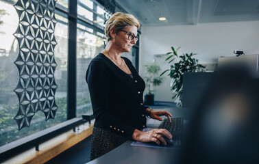 Senior businesswoman working at standing desk in office