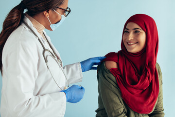 Smiling muslim woman getting vaccinated