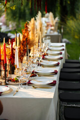 Decorated outdoors nature banquet table set with candles and dried flowers