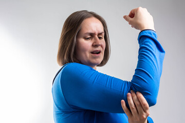 female massaging painful hand indoors. woman hand holding her elbow suffering from elbow pain. woman suffering from pain in hand at home. woman's hand holding her elbow. Elbow pain concept.