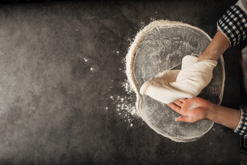 Hands making a pizza dough with flour on the grey concrete background