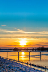 Fototapeta na wymiar Sunset landscape with frozen floodplains in The Netherlands