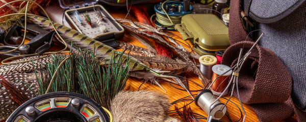 Banner Fly Fishing Still Life. Materials and tools for tying lures on a wooden table. Hobby concept.