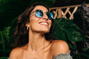 Happy ethnic woman enjoying sunny day in exotic garden