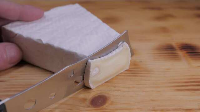 cutting camembert brie cheese with knife 