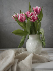 Crimson color tulips bouquet. Spring bouquet of pink tulips . Spring flowers bouquet in a white vase . Pink tulips on a grey background with a copy space. 