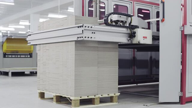 Conveyor line for the production of boxes. Machine carves and bends cardboard boxes from sheets of cardboard. Enterprise for the production package
