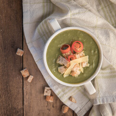 Spinach soup on a wooden table with croutons .