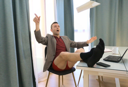 Happy slacker with feet on table flying a paper airplane while supposed to be working from home