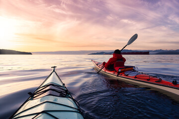 Adventurous Man Sea Kayaking in the Pacific Ocean. Dramatic Colorful Sky Art Render. Taken in...