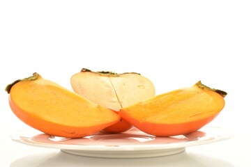 One juicy cut persimmon on a white saucer, close-up, isolated on white.