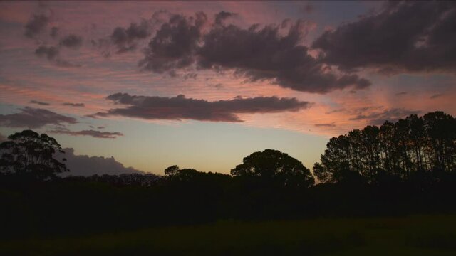 timelapse of clouds moving over the silhouetted trees