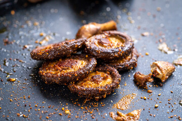 Fried shiitake mushrooms on iron plate on dark background
