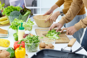 Young couple preparing a meal chopping vegetables in kitchen at home, healthy lifestyle.