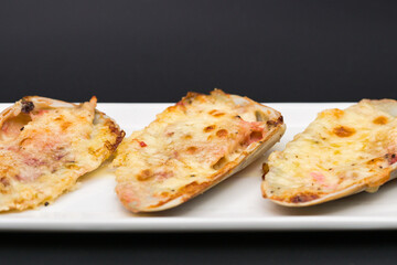 (machas a la parmesana) seashell cooked in parmesan. served on a white plate