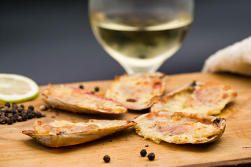 (machas a la parmesana) seashell cooked in parmesan. served on a wooden board