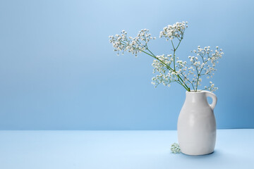 White vase with flowers on a blue background. Ball candies, sweets in a vase. Place for your text.