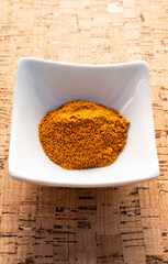 turmeric in a small white bowl on cork background