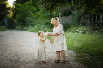 Fototapeta premium Grandmother and granddaughter walk around the park in white vintage clothes