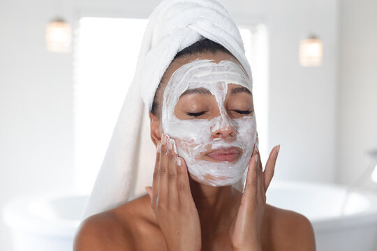 African american woman applying face mask in bathroom