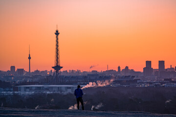Fototapeta na wymiar silhouette of a person on a hill above the city of berlin during sunset