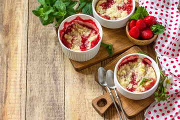 Summer dessert home cooking. Strawberries crumble in a baking dish and fresh strawberries on a wooden rustic table. Copy space.